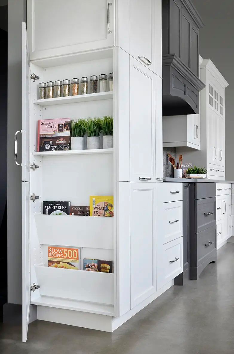 A kitchen with white cabinets and a pantry with a pull out drawer.