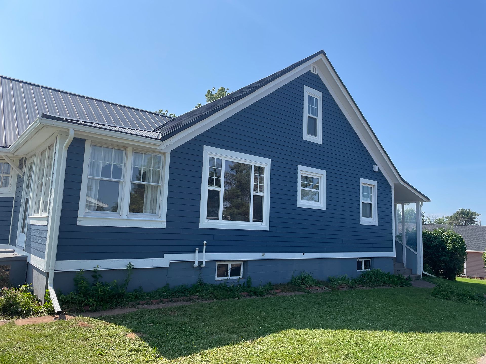 A blue house with white trim and windows is sitting on top of a lush green lawn.
