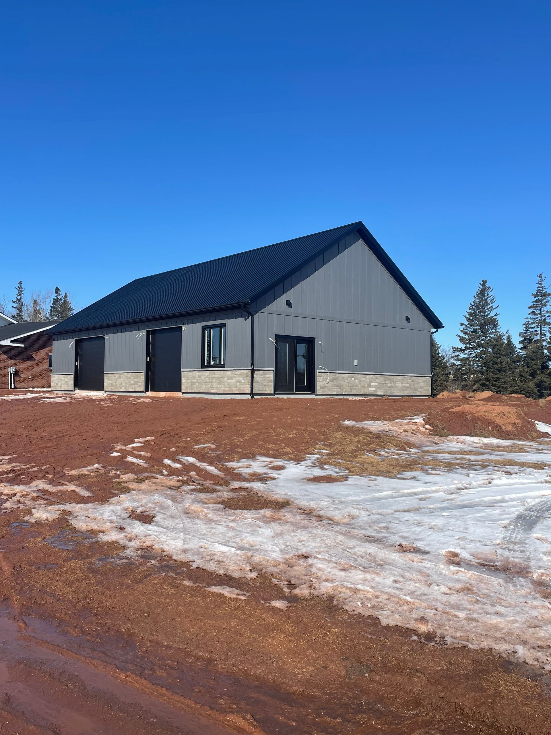 A small house with a black roof is sitting on top of a dirt hill.