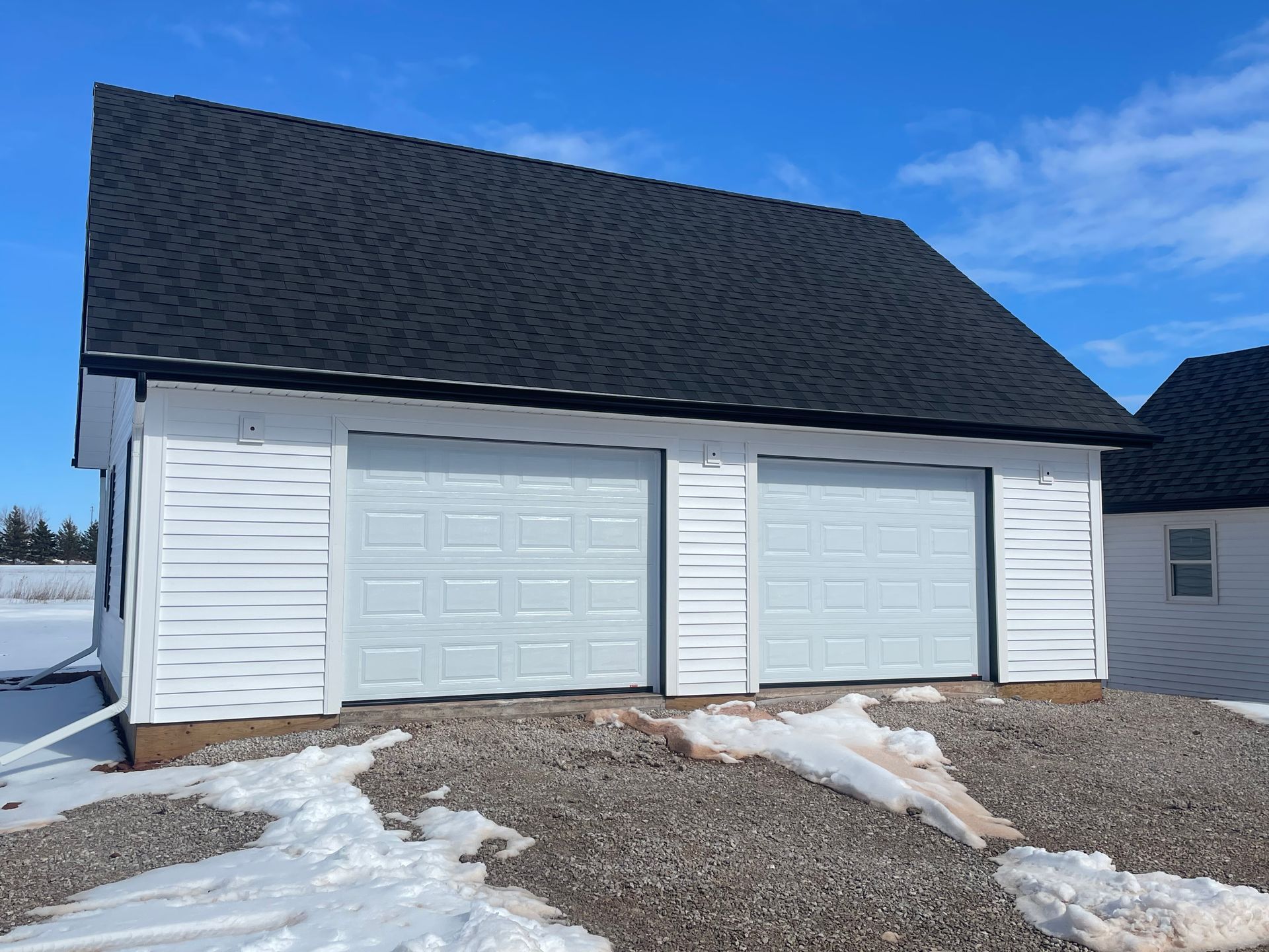 A white garage with a black roof and white garage doors