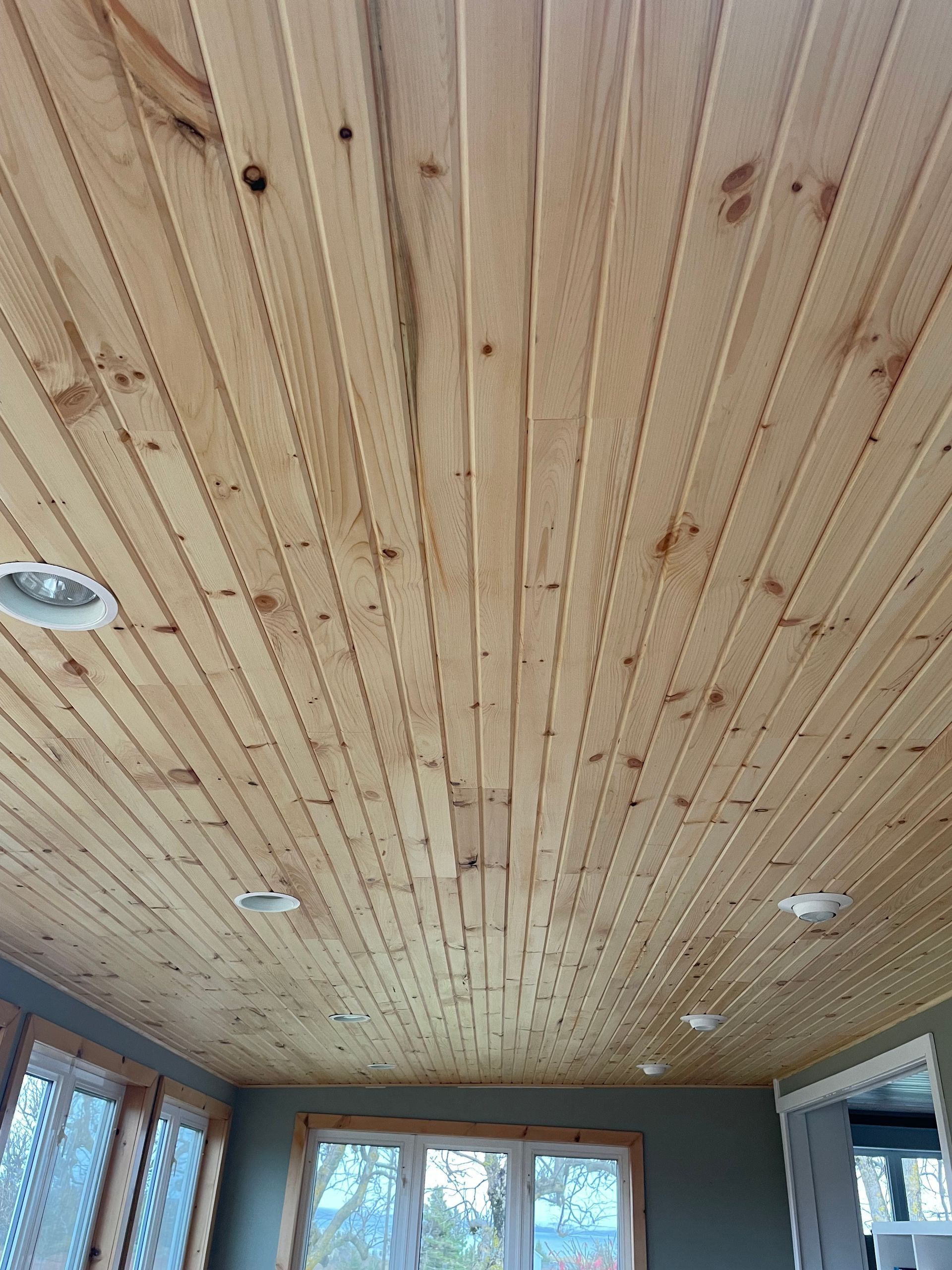 A wooden ceiling in a room with a lot of windows.