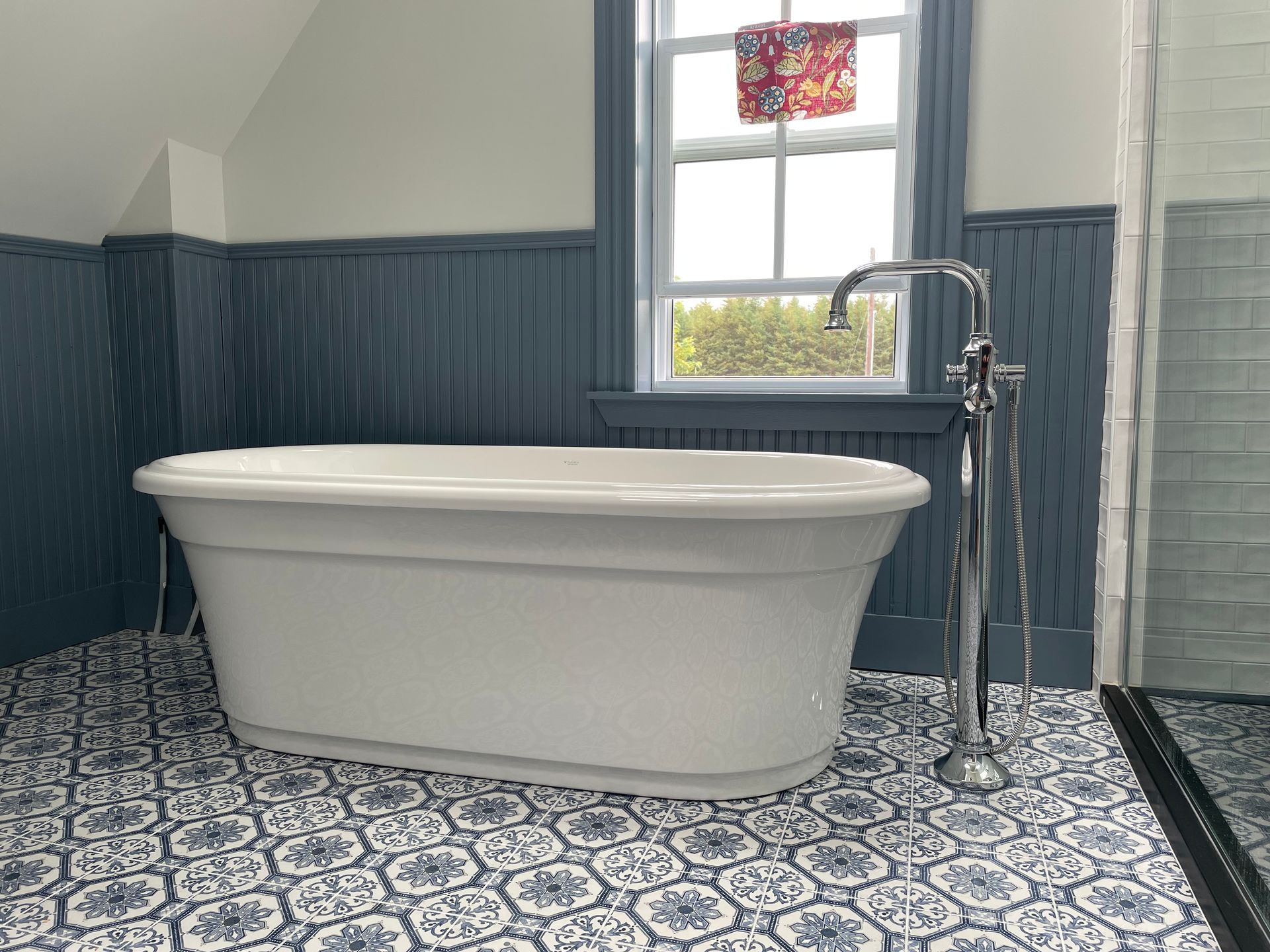 A white bathtub is sitting in a bathroom next to a window.