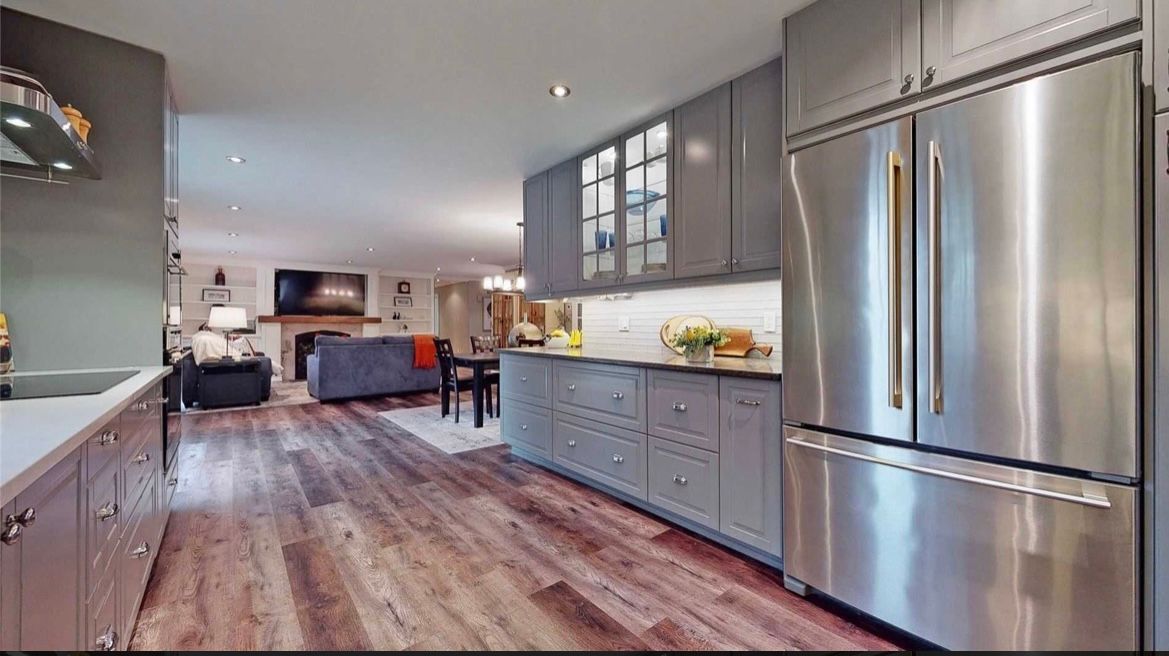 A kitchen with stainless steel appliances and wooden floors.