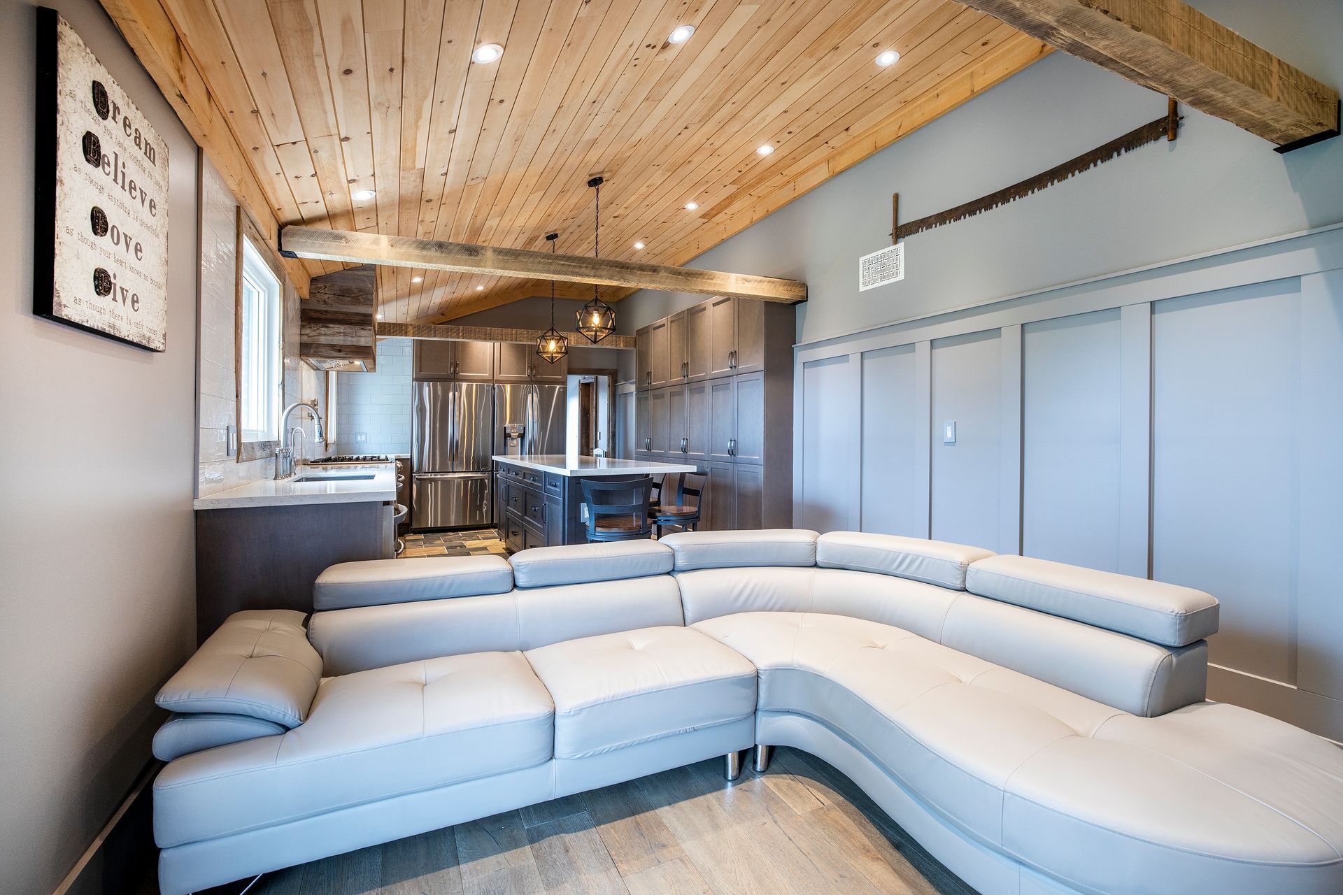 A living room with a large sectional couch and a kitchen in the background.