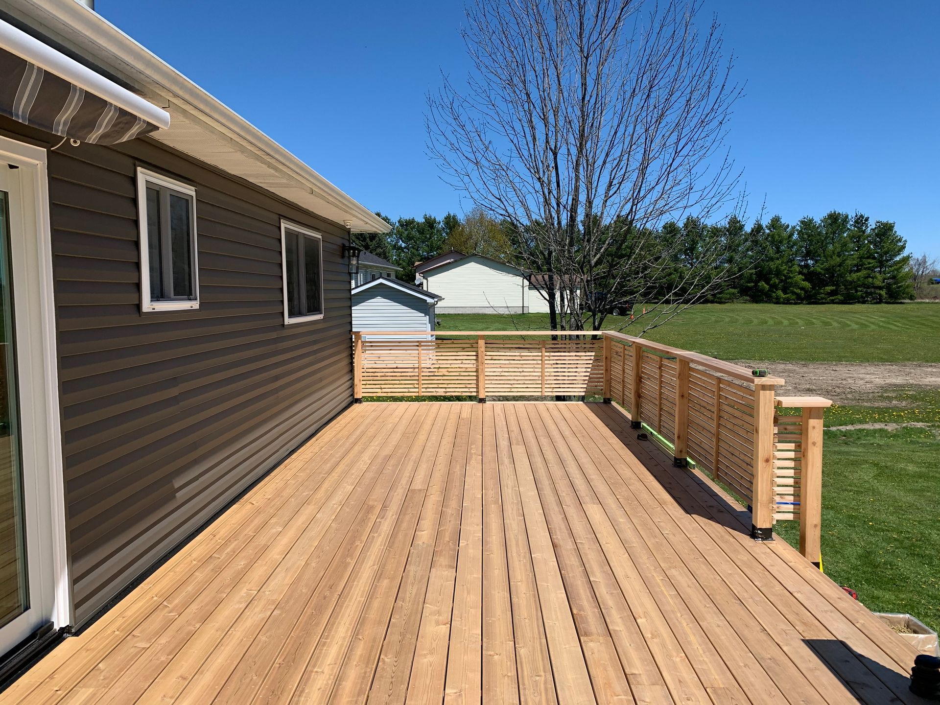 A large wooden deck is sitting in front of a house.
