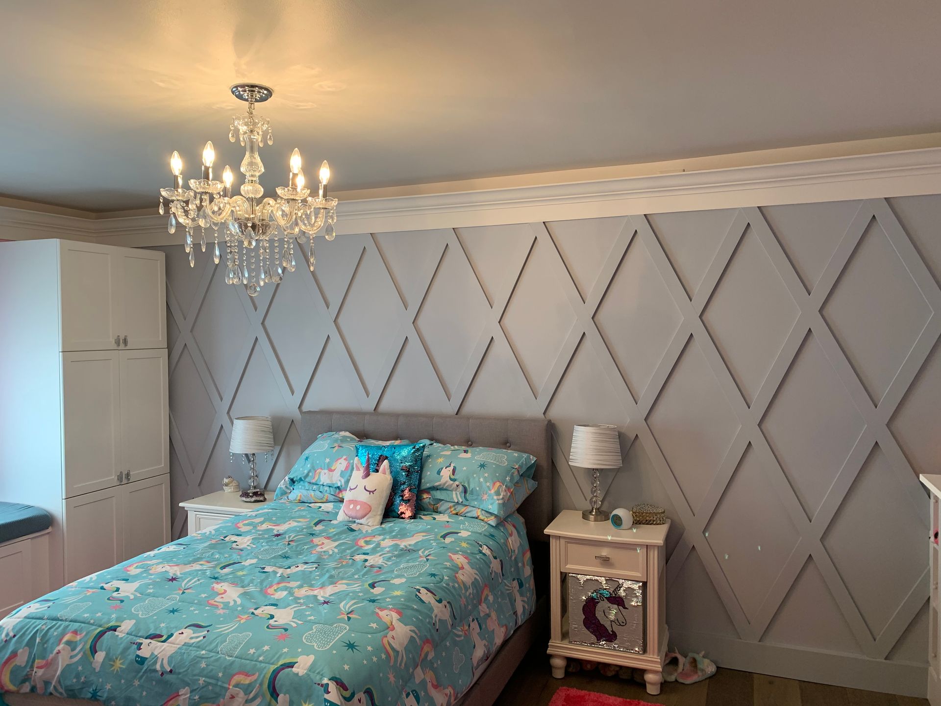 A bedroom with a bed , nightstand , and chandelier.