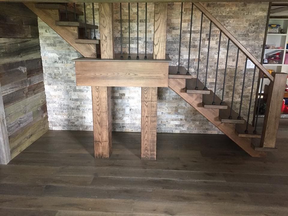 A wooden staircase in a room with a brick wall