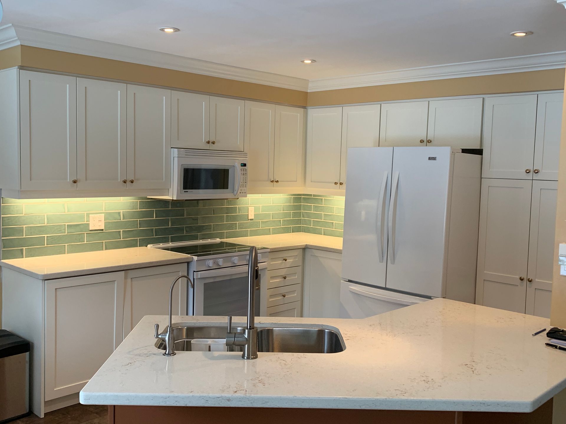 A kitchen with white cabinets and a stainless steel sink