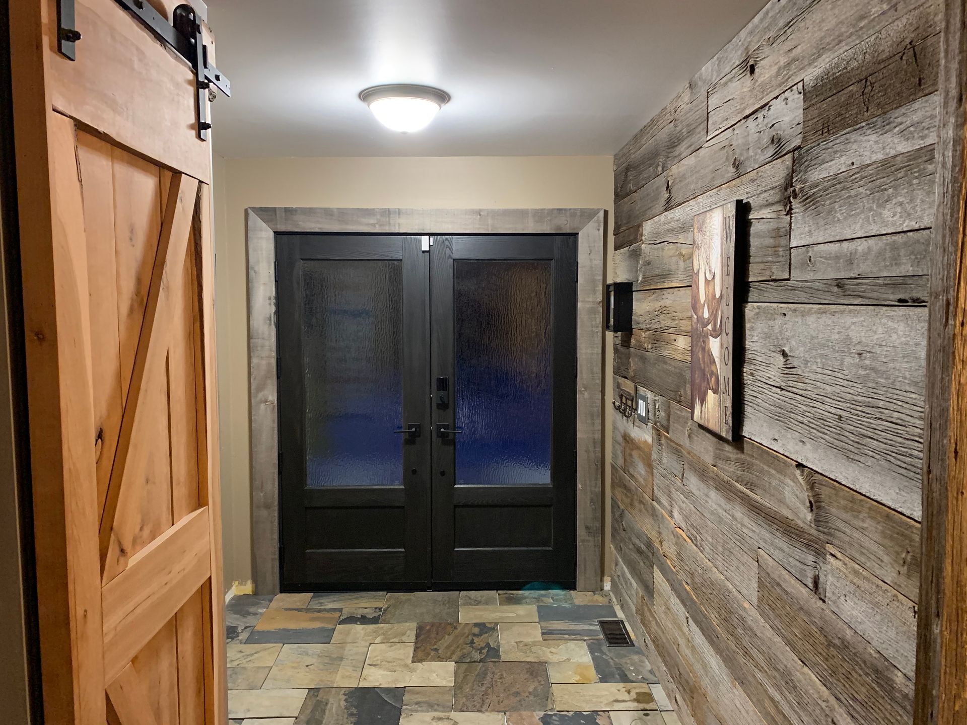 A hallway with a sliding barn door and a wooden wall.