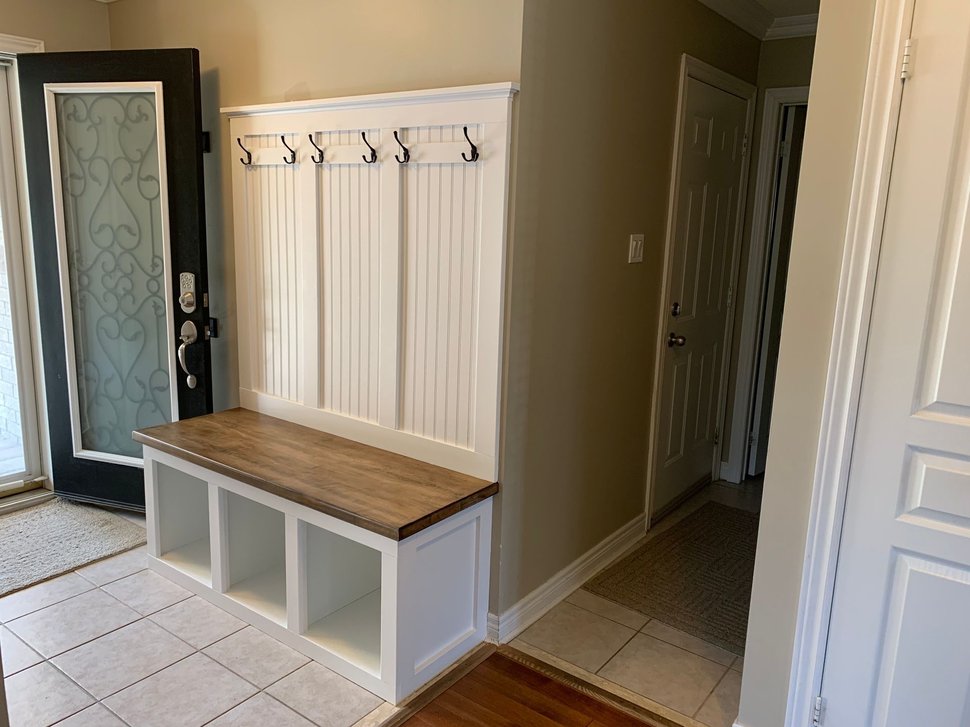 A hallway with a bench and hooks on the wall.
