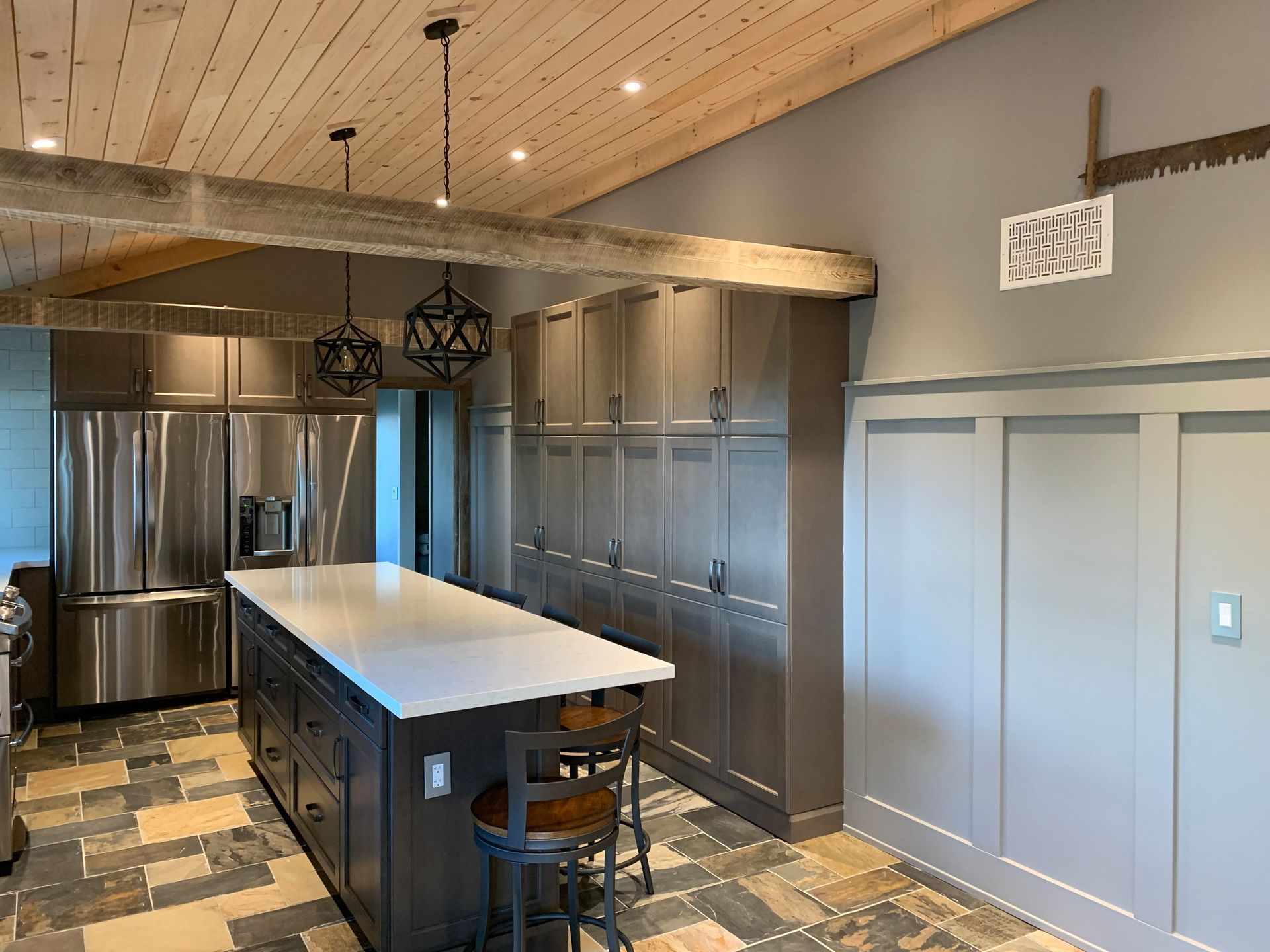 A kitchen with stainless steel appliances and a large island in the middle.