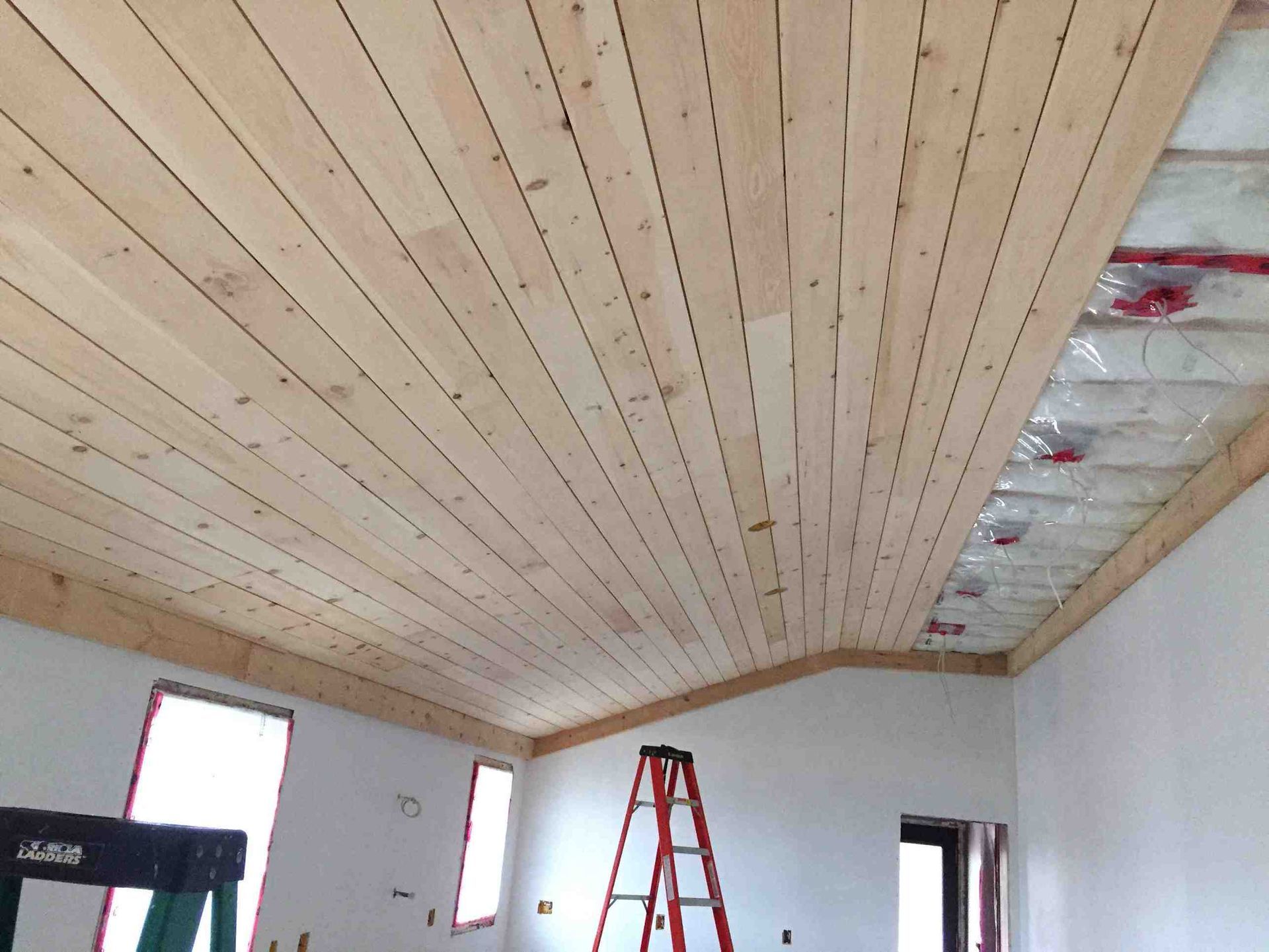 A room with a wooden ceiling and a ladder