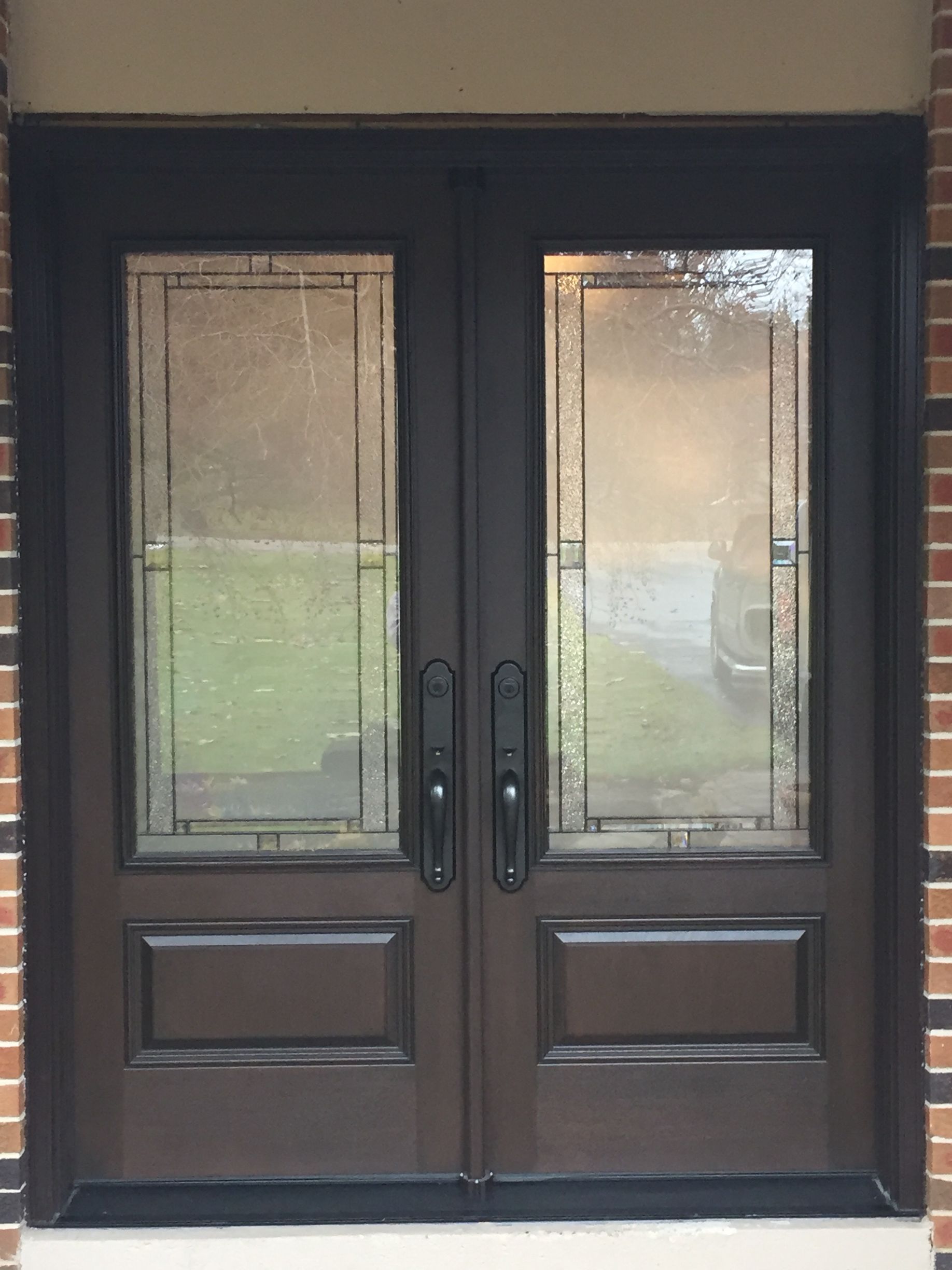 A brown double door with stained glass on a brick building