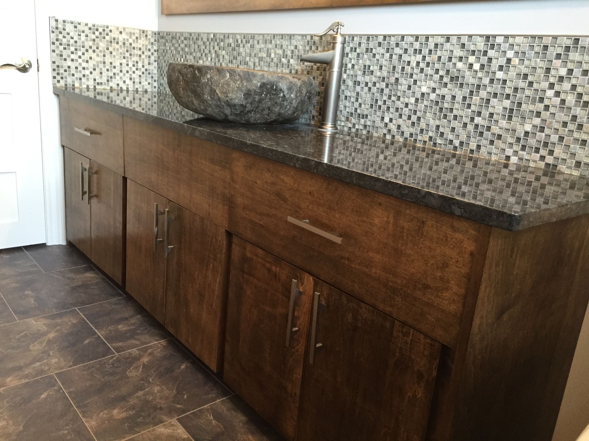 A bathroom vanity with a stone sink on top of it
