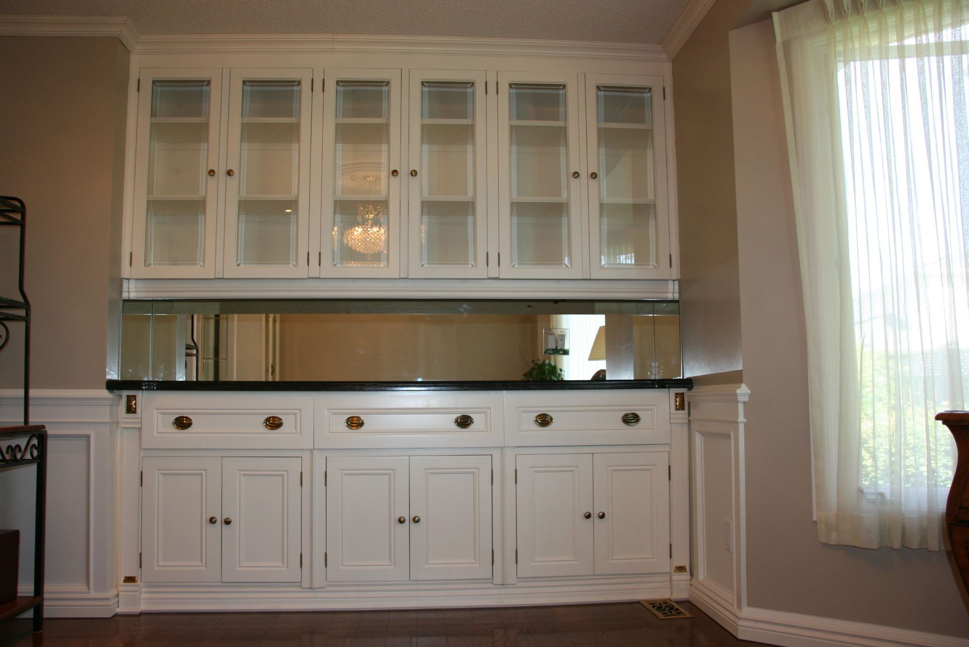A dining room with white cabinets and a black counter top