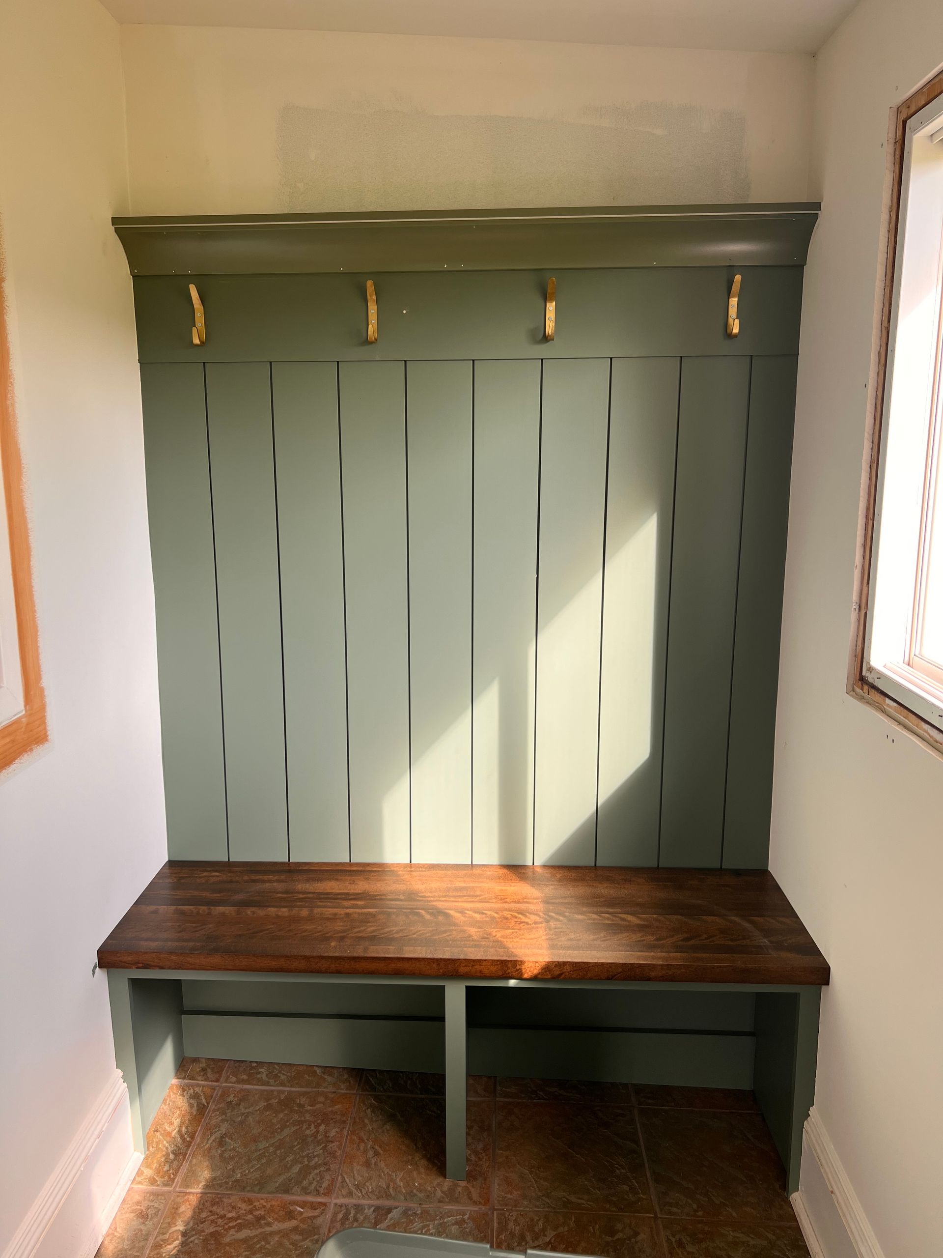 A room with a bench and a wall with hooks on it