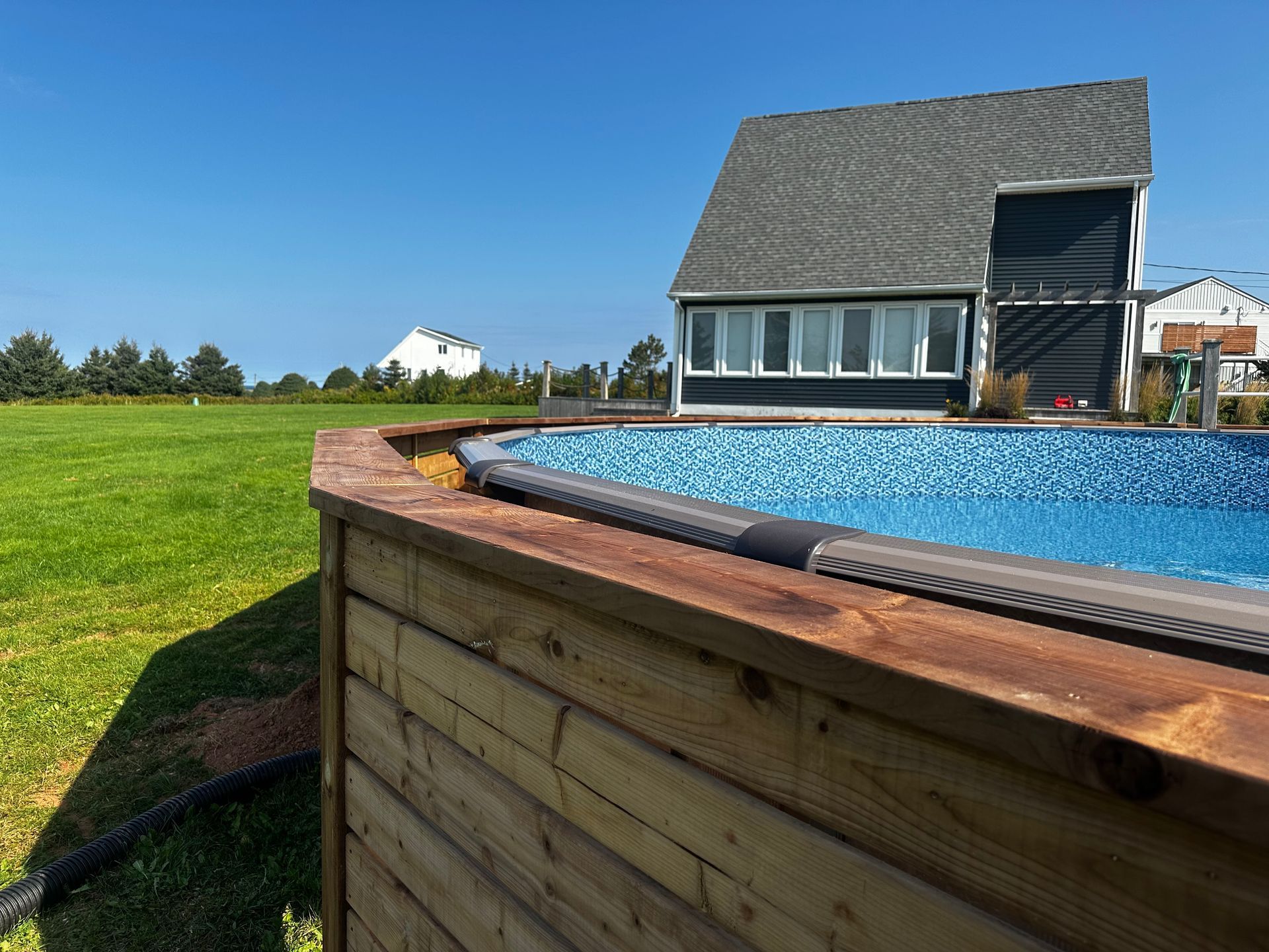 A large swimming pool is sitting in front of a house.