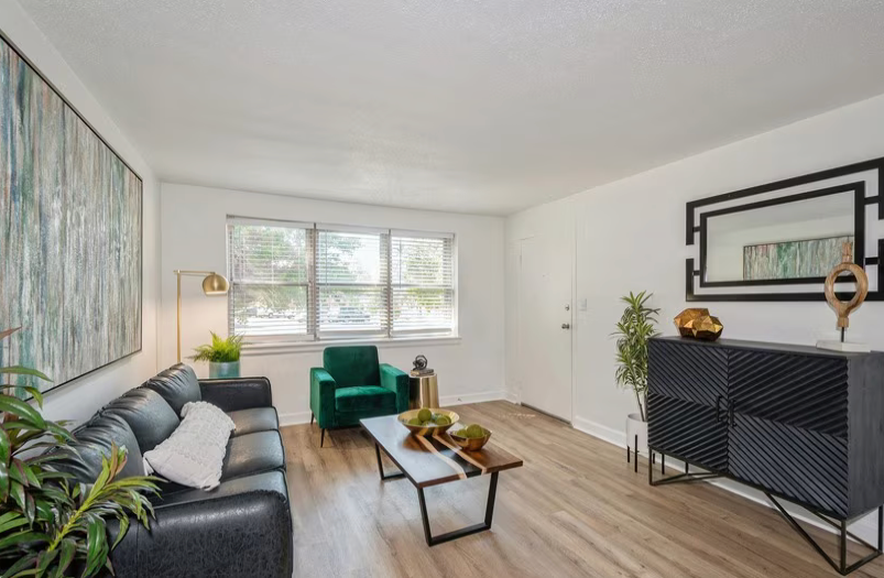 Living room with black leather sofa, green chair, wood and metal coffee table, and patterned cabinet.