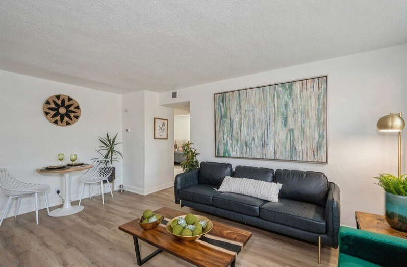 Living room with black sofa, artwork, table and chairs.