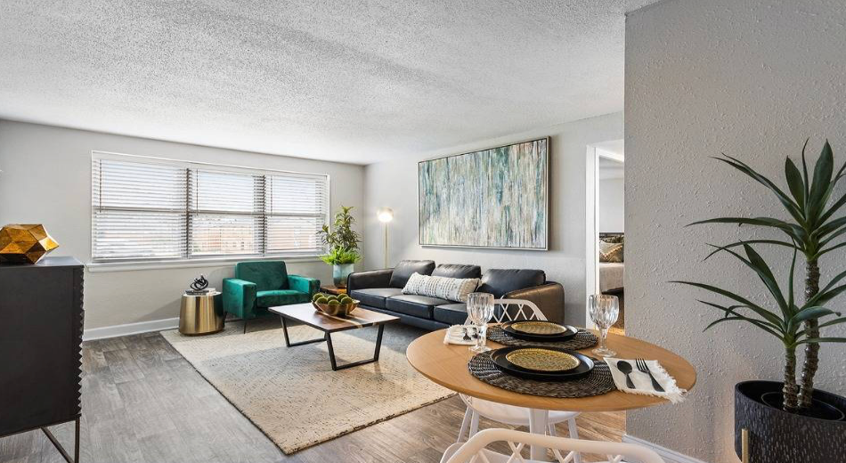 Living room with a dining area, featuring a couch, teal chair, and abstract artwork.