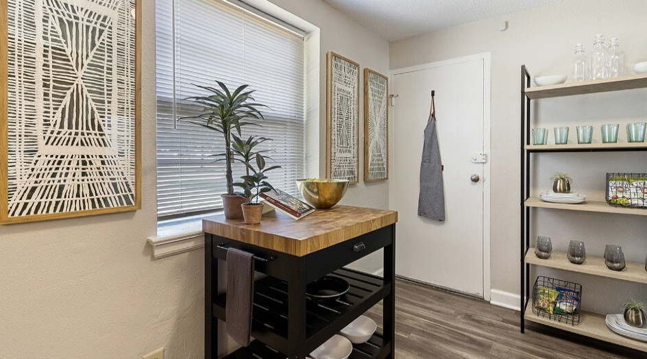 Kitchen area with a butcher block island, shelving, window, and door.