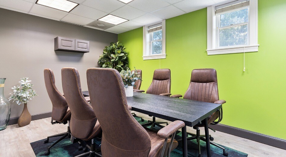 Conference room with a dark table, brown chairs, and lime green walls.