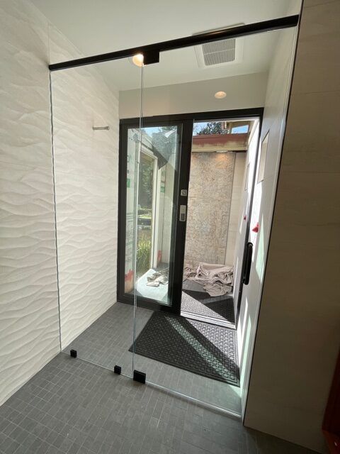 A room with a glass door and a mirror on the wall.