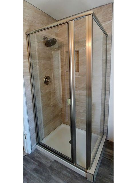 A shower stall with sliding glass doors in a bathroom.