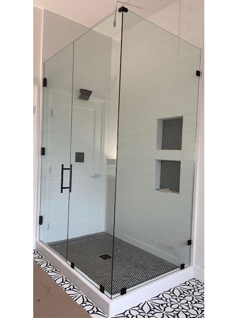 A bathroom with a walk in shower with a glass door