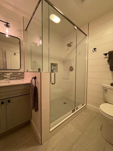 A bathroom with a toilet a sink and a walk in shower