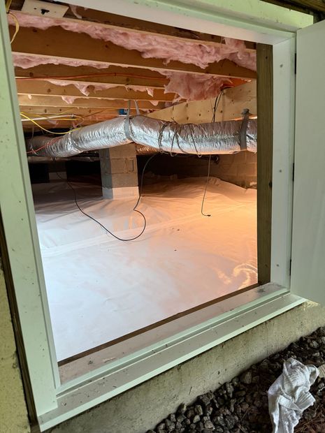 Basement window view of exposed insulation, ductwork, and unfinished floor framing