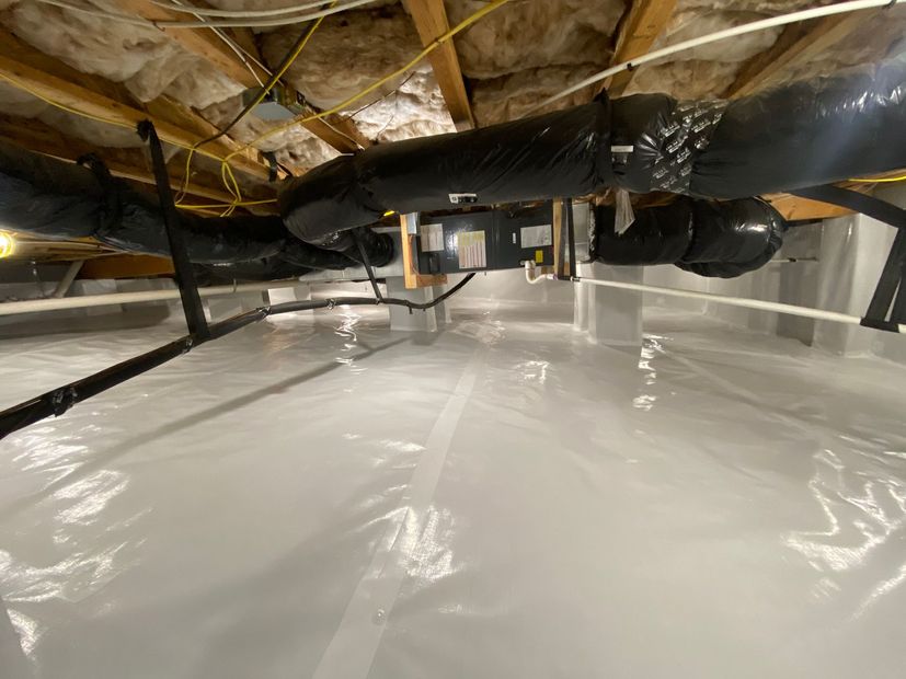 Plastic-covered crawl space with exposed insulation, pipes, and ductwork under a house