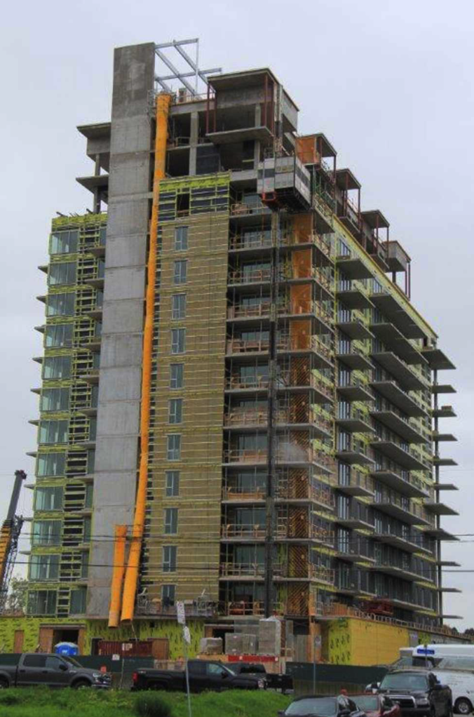 A tall building under construction with cars parked in front of it