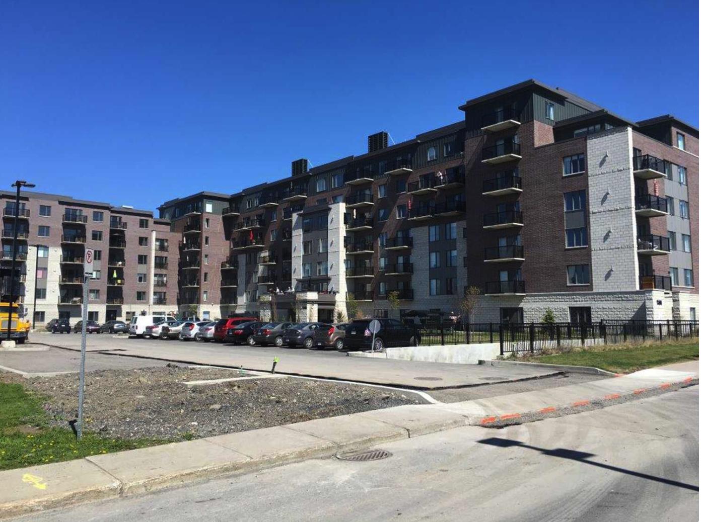 A large apartment building with a lot of cars parked in front of it