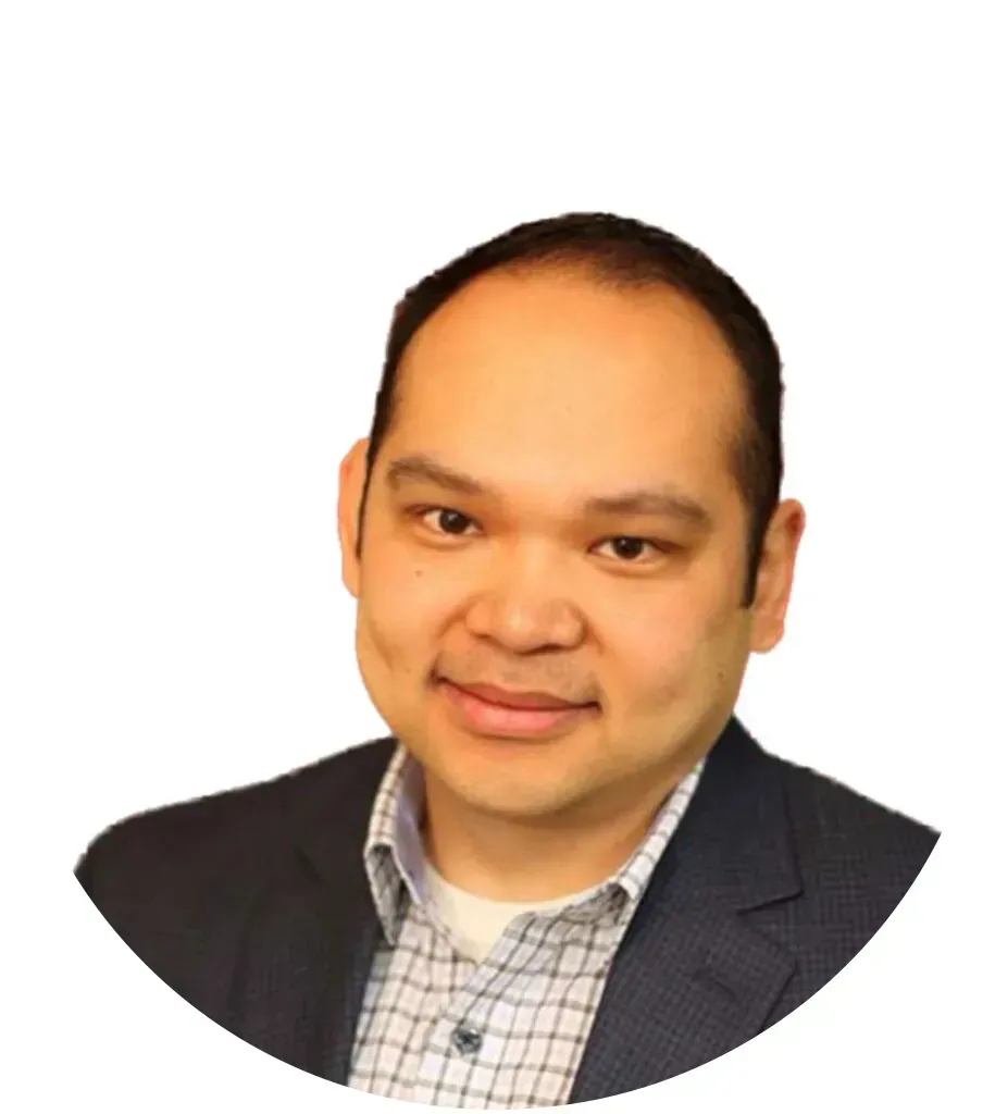 Man in blazer and checkered shirt smiles, head and shoulders portrait.