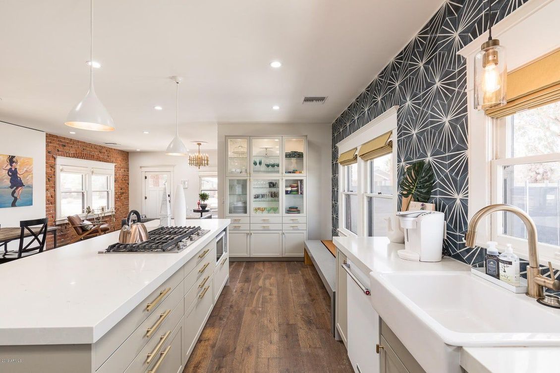 A kitchen with white cabinets , a large island , a sink , and a lot of windows.