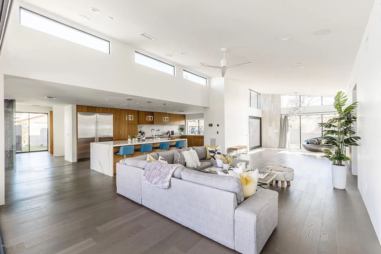 A living room filled with furniture and a kitchen in a modern house.