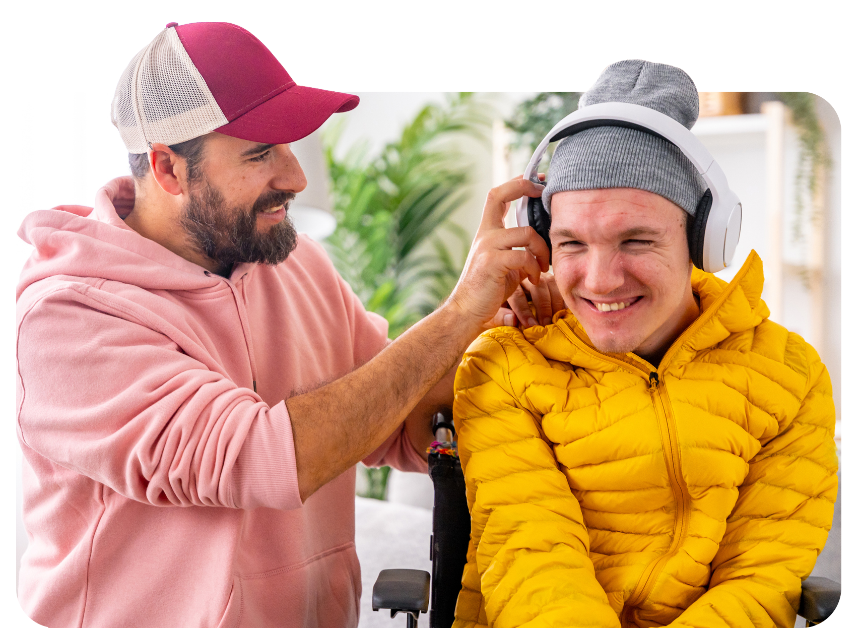 Man adjusting headphones on another person, both smiling, indoor setting.