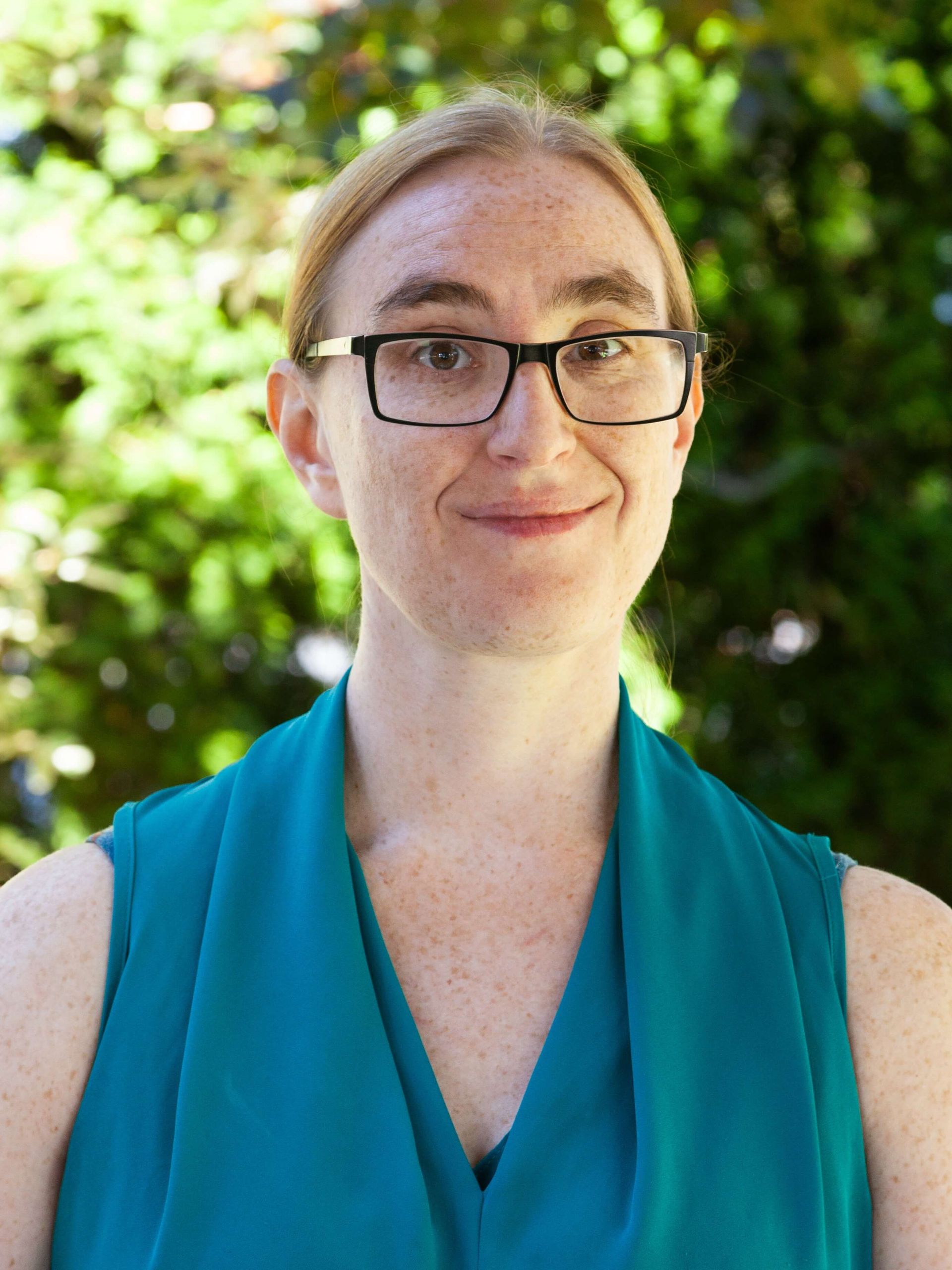 Woman smiling and wearing glasses with her hair up.