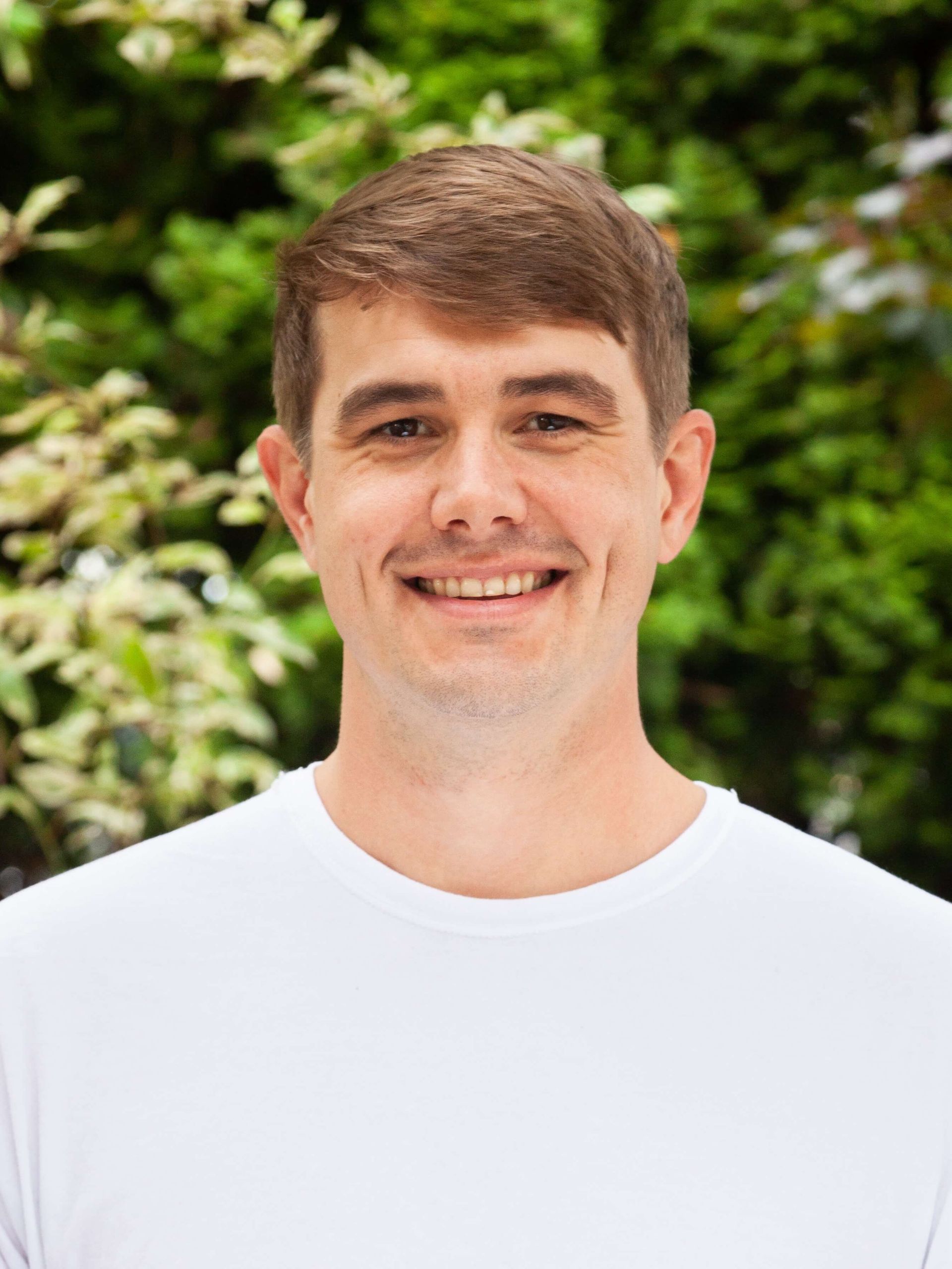 Man smiling in white tee shirt.