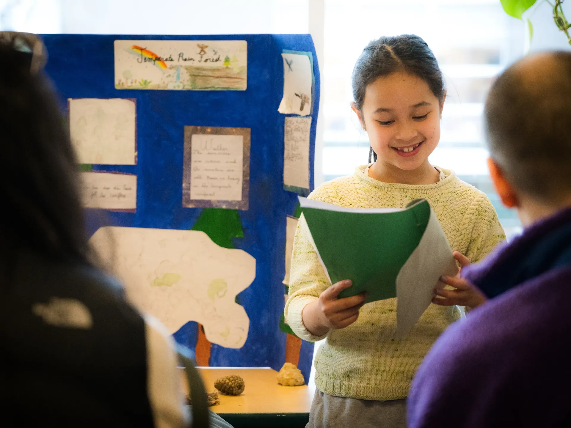 Elementary student presenting her work with a smile.