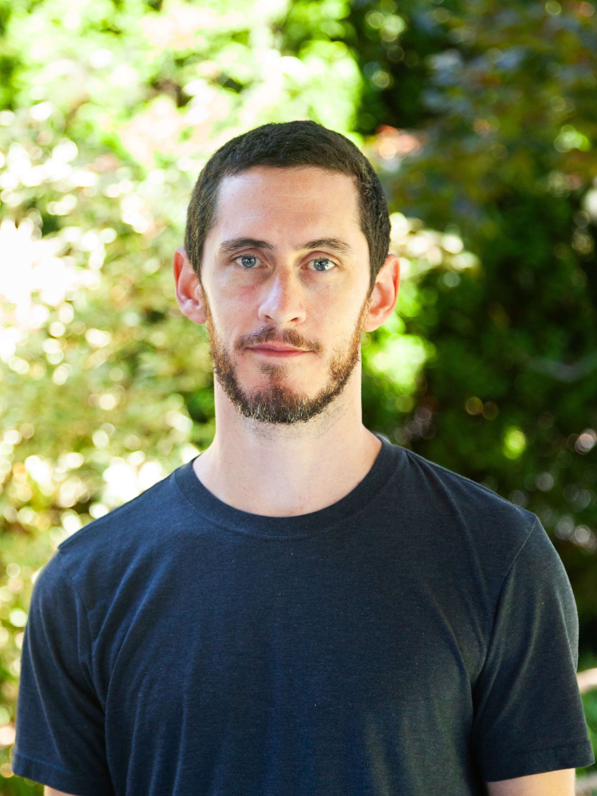 Man with dark tee shirt and some facial hair.