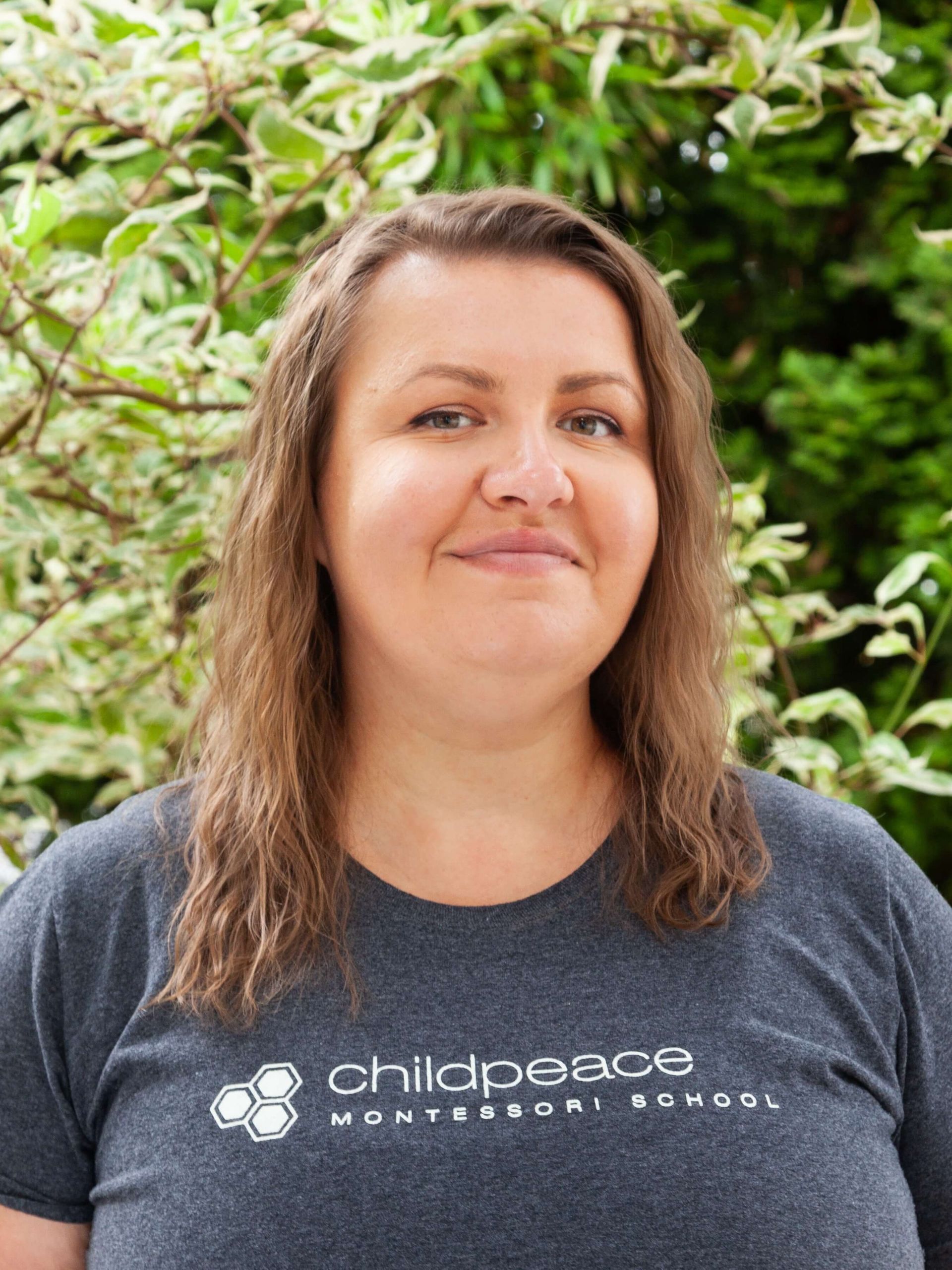 Woman smiling with medium length wavy brown hair.