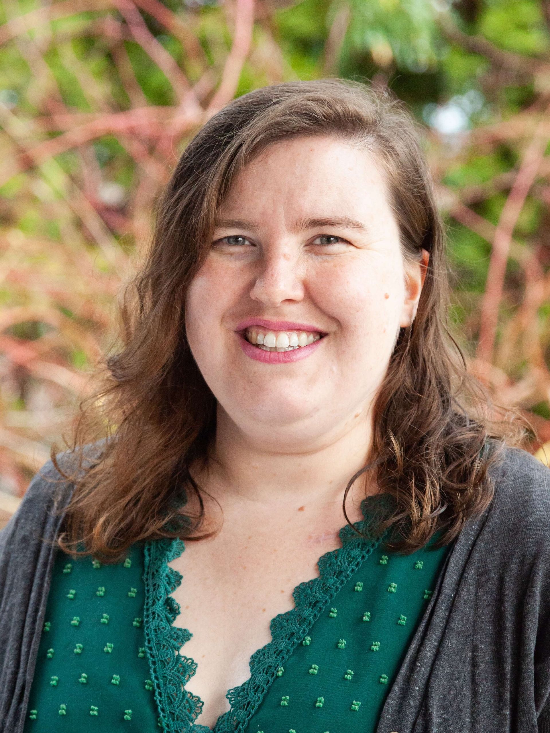 Woman smiling with wavy brown hair.