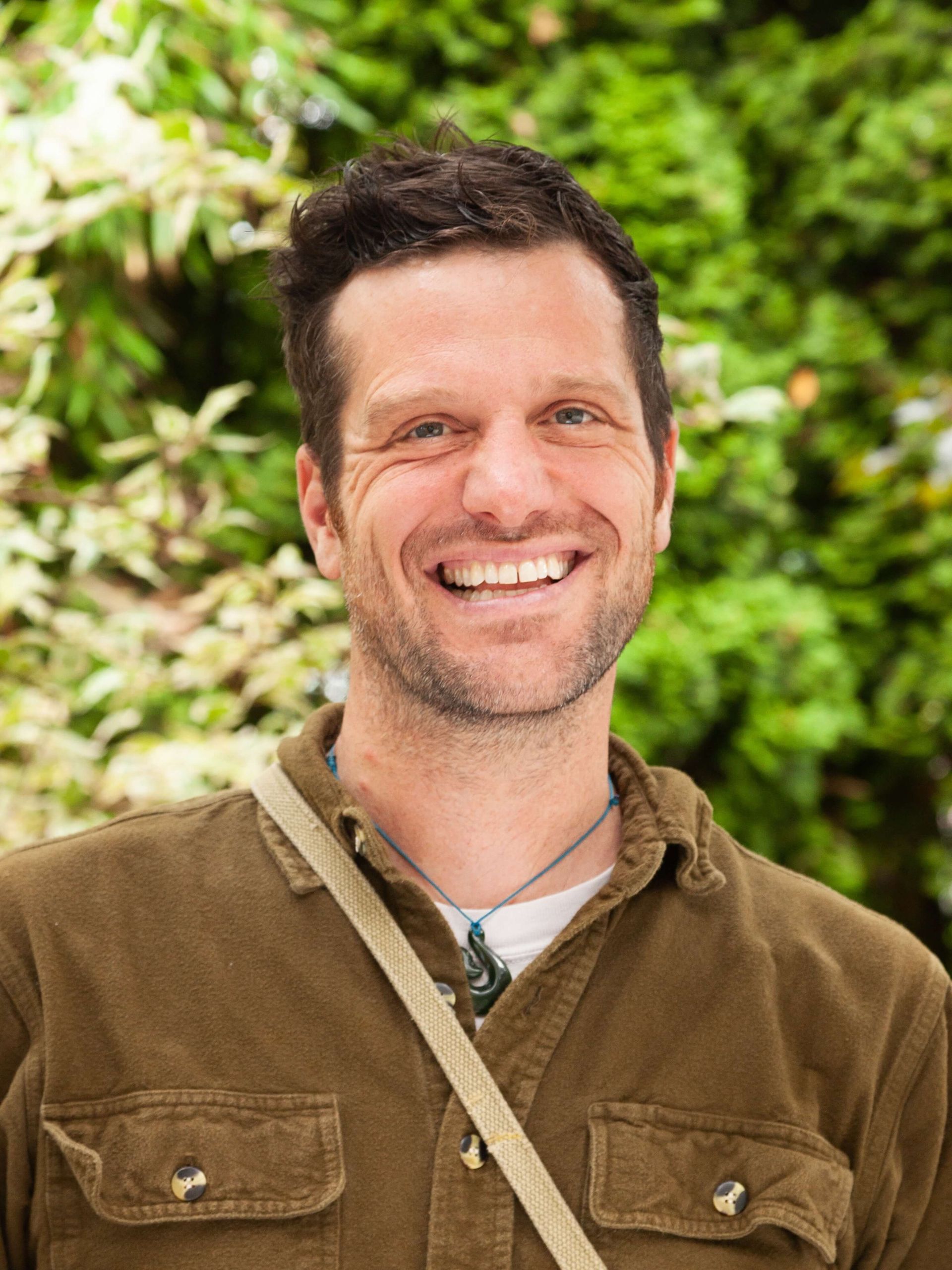 Man in utility shirt smiling.