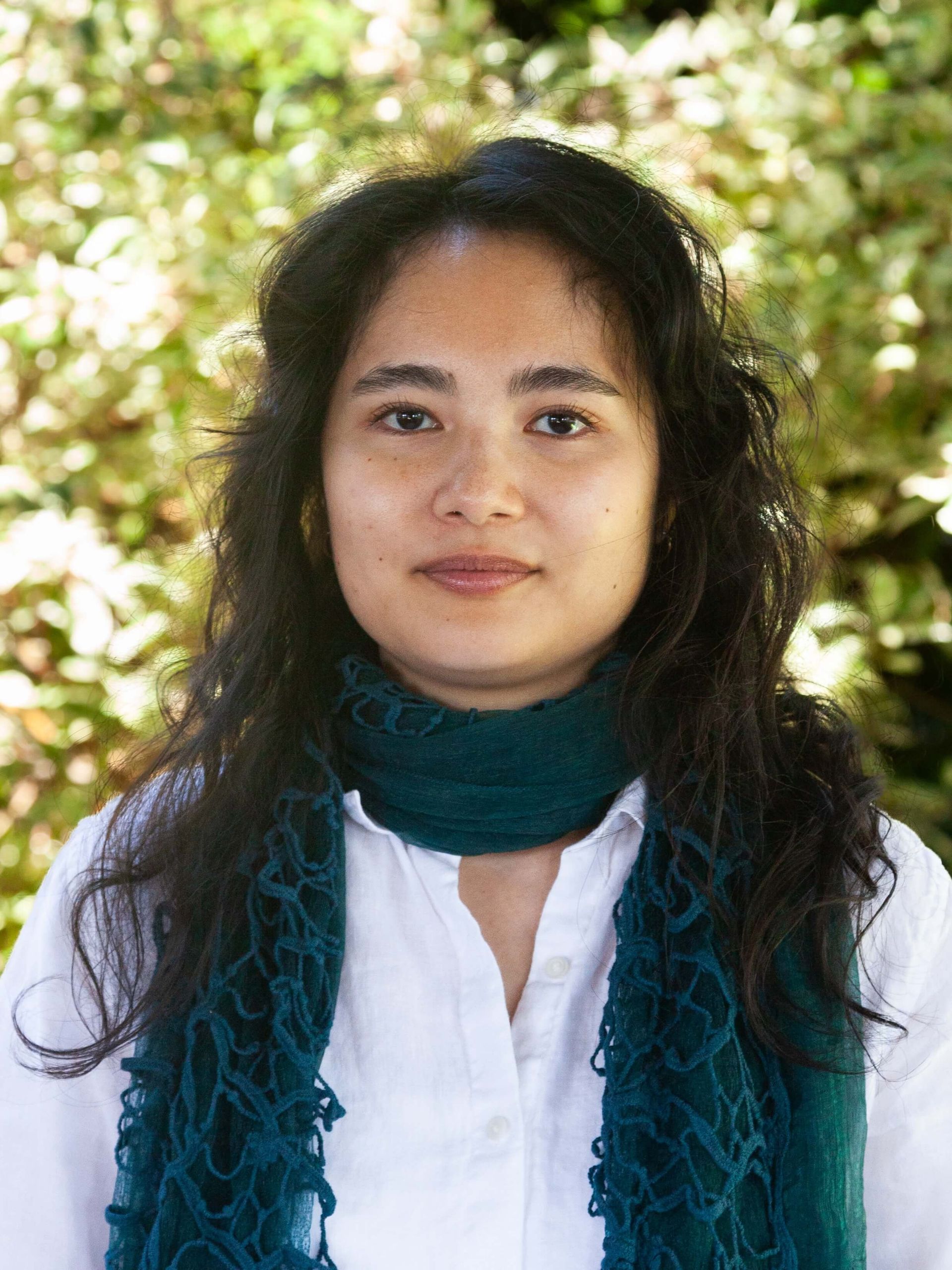 Woman with curly brown hair wearing a scarf. 