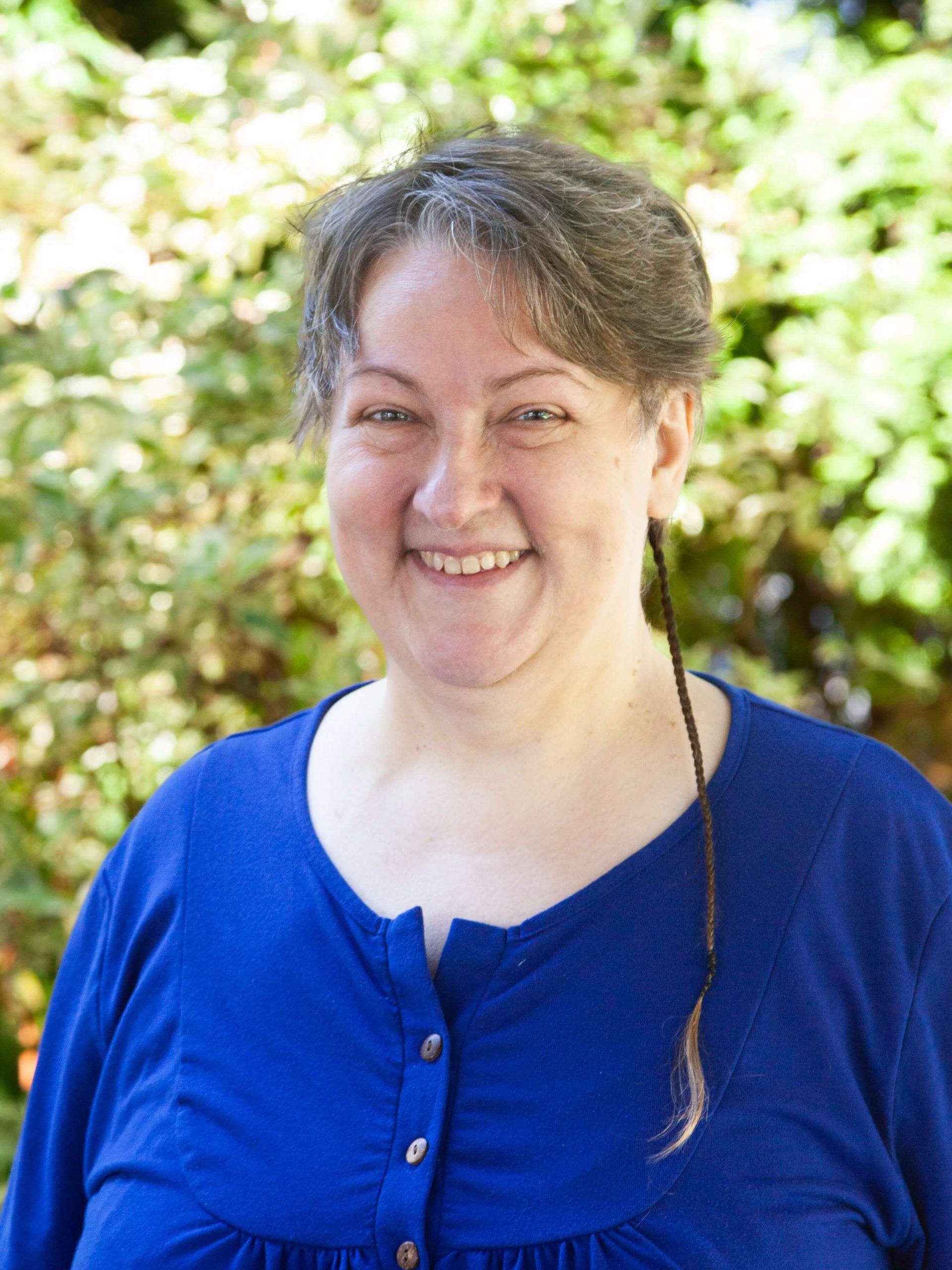 Woman with short hair in purple blouse smiling. 