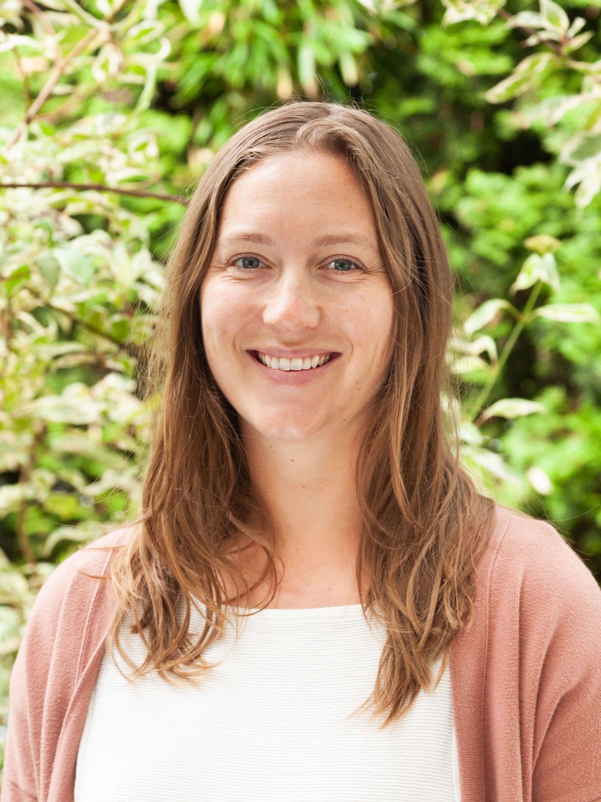 Woman smiling and wearing a peach colored sweater. 