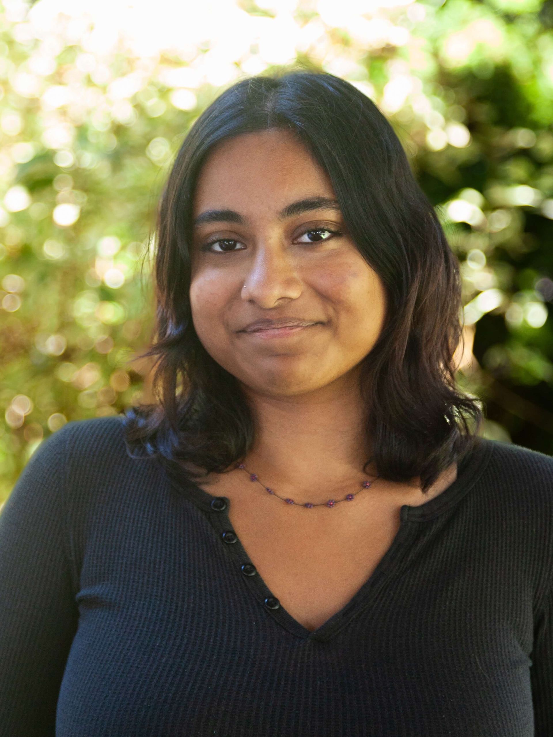Woman smiling with black shirt and medium length dark hair.