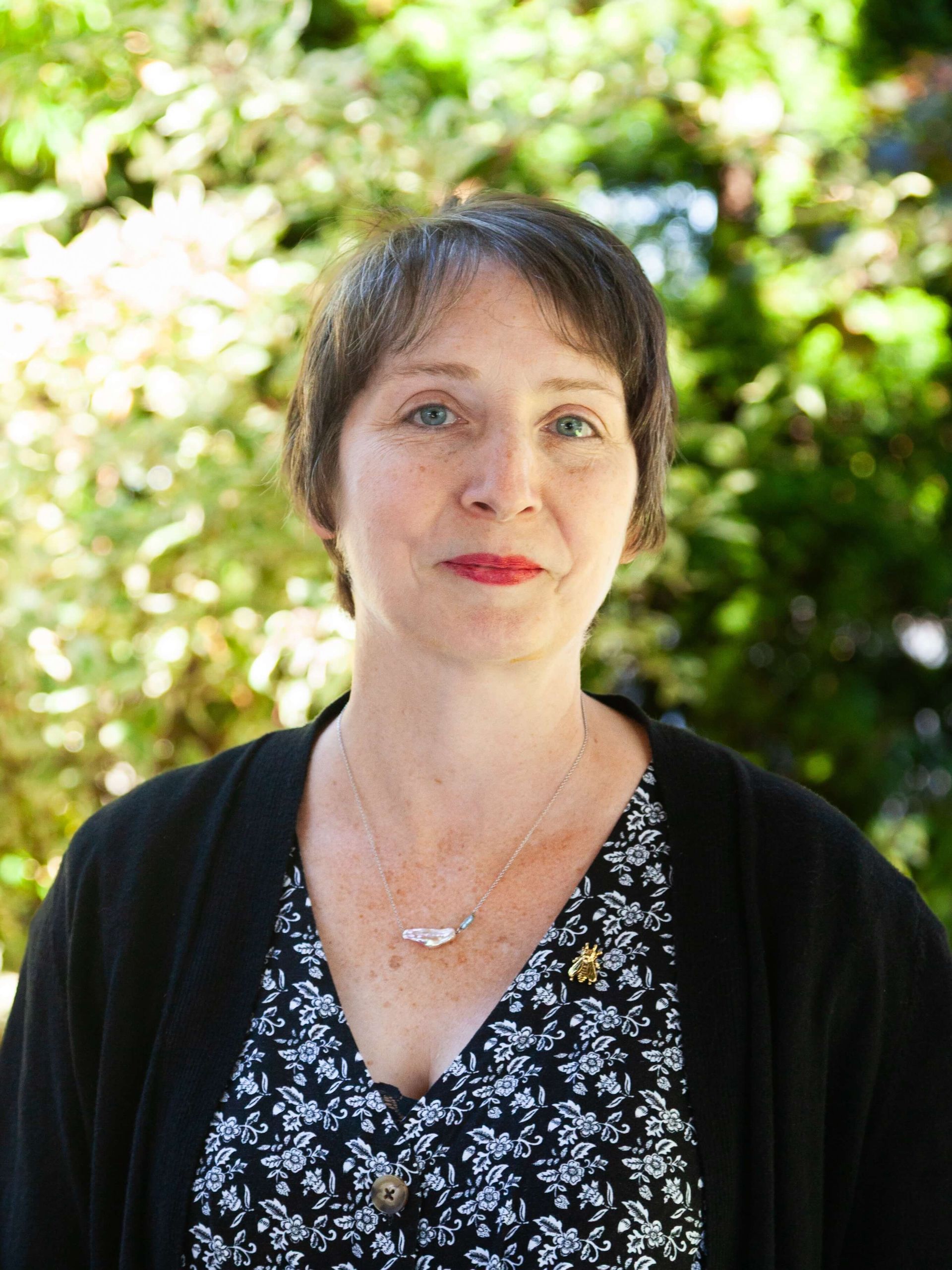 Woman with short hair and red lipstick gently smiling. 